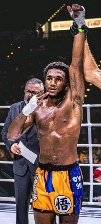 Boxer celebrating a victory in a boxing ring with a referee and crowd in the background.